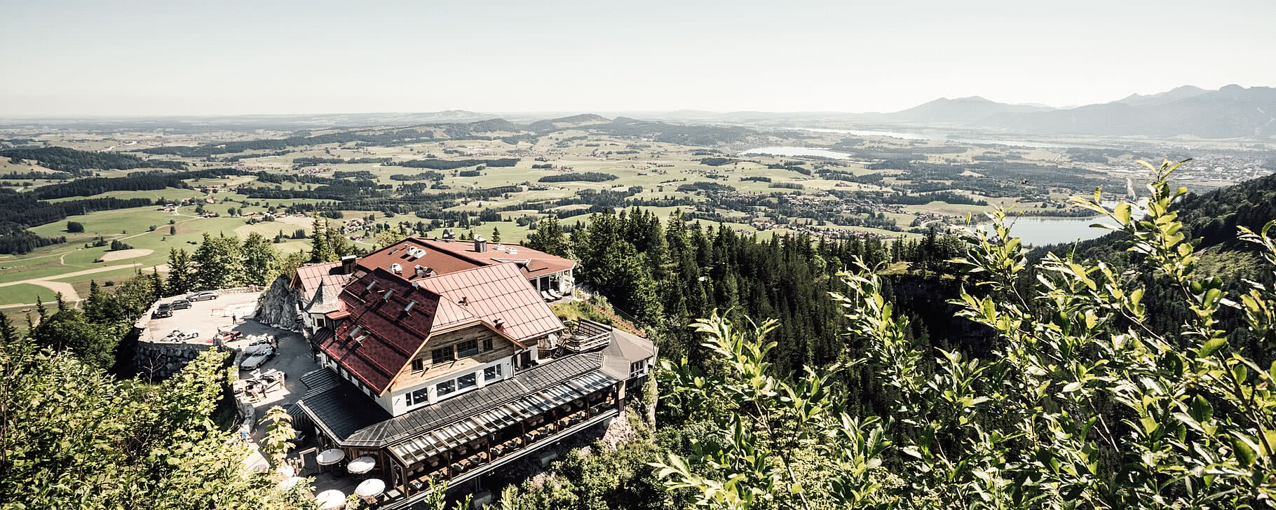 Die Blaue Burg Falkenstein thront majestätisch über der grünen Landschaft des Allgäus, umgeben von Wäldern und Bergen.